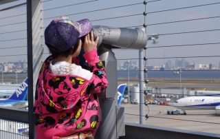 An AvGeek-in-training uses a telescope on HND T2's observation deck. See the cables?